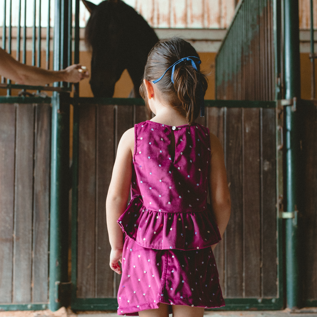 little girl back wearing a Piglo Kids velvet top and skirt outfit with sequins